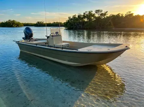 A compact 14-foot flat-bottom skiff on a clear saltwater flat at golden hour.